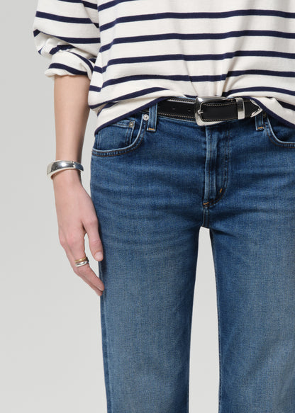 Person wearing a striped shirt and blue jeans on a grey background