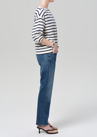 Person wearing a striped shirt and blue jeans on a grey background