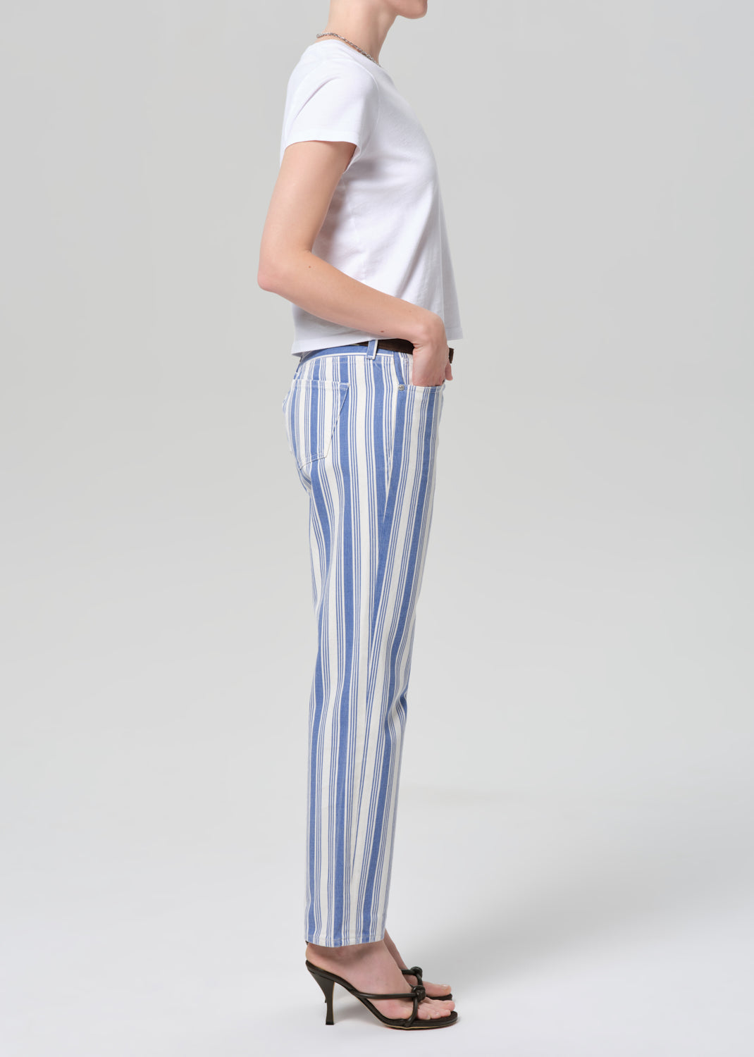 Person wearing a white t-shirt and blue striped pants on a plain background