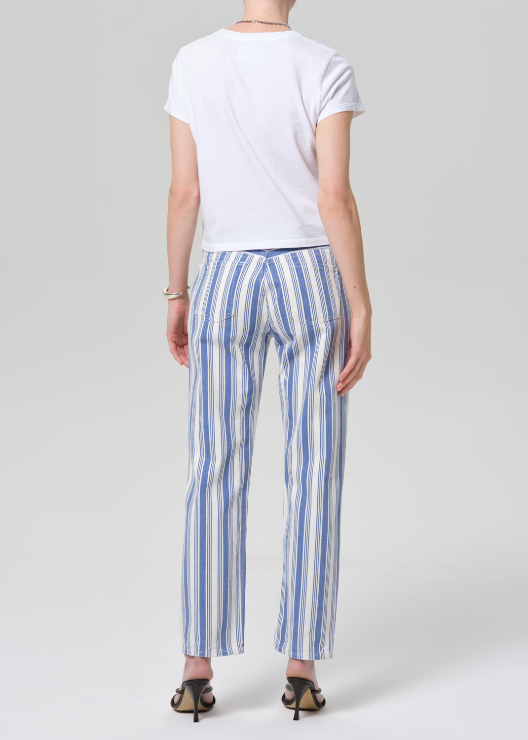 Person wearing a white t-shirt and blue and white striped pants on a plain background