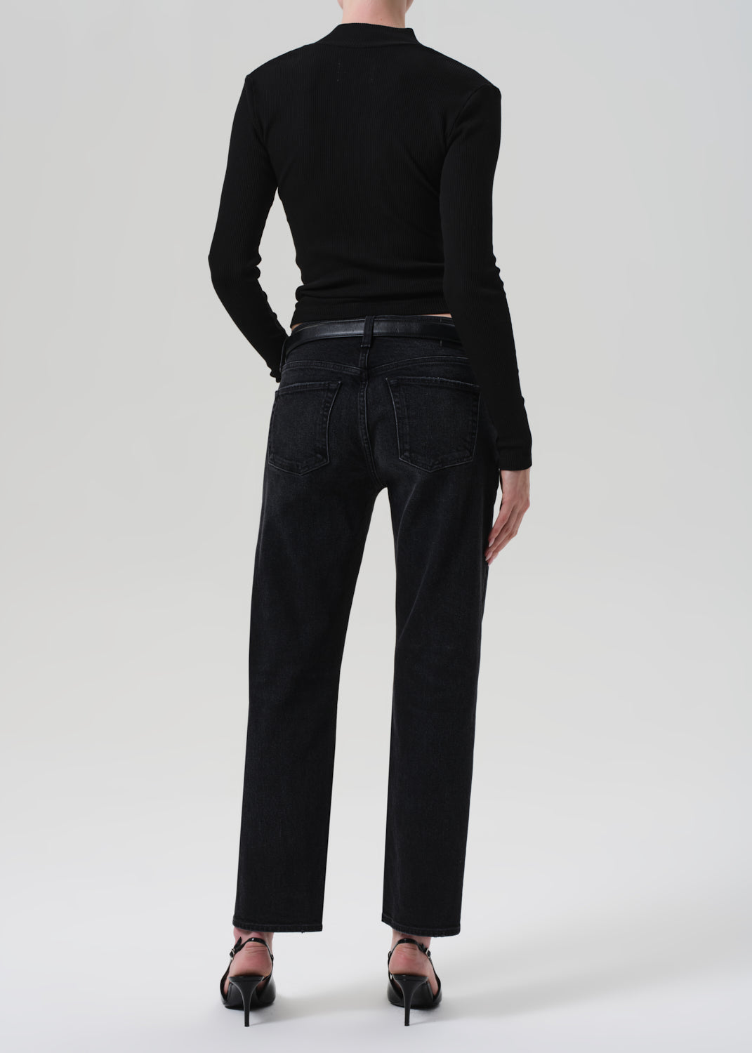 Person wearing a black henley and black jeans on a white background