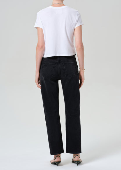 Person wearing a white top, black jeans, and a gray sweater on a plain background