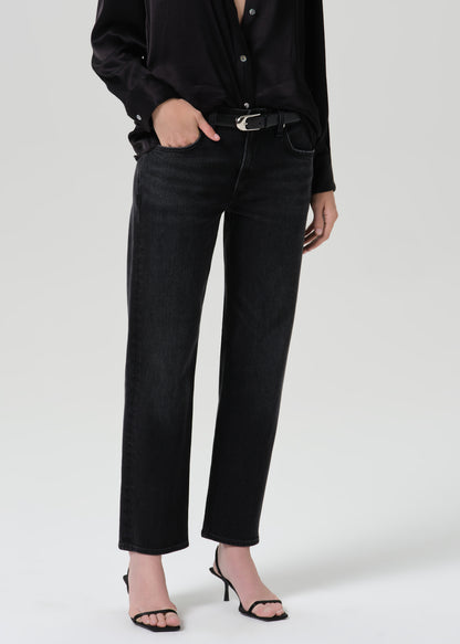 A model wearing black wide-leg cropped jeans with a black shirt and black heeled sandals, shown from the chest down against a grey background.