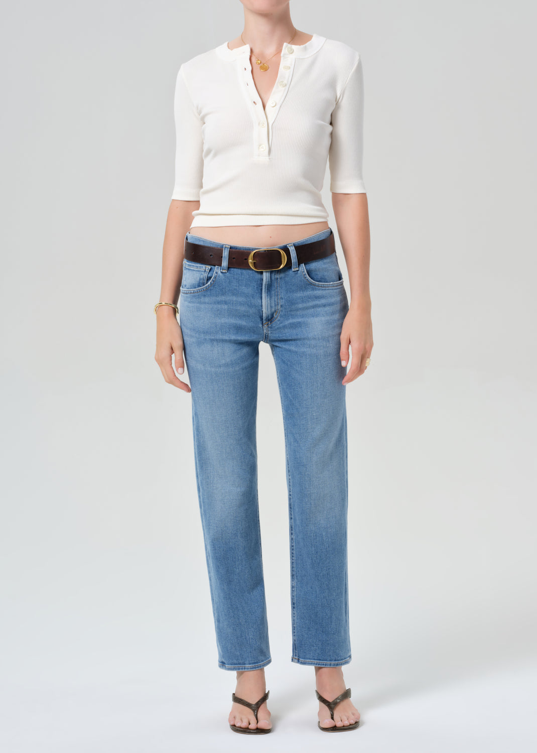 Person wearing a white top and blue jeans on a plain background