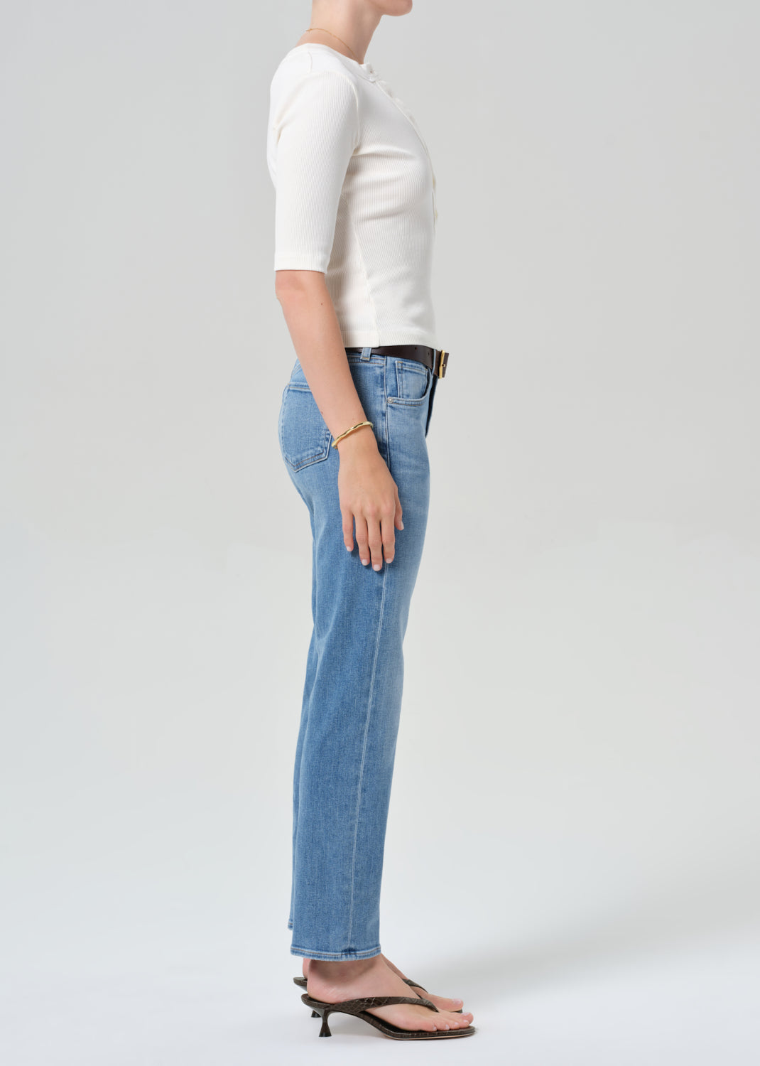 Person wearing a white top and blue jeans on a plain background
