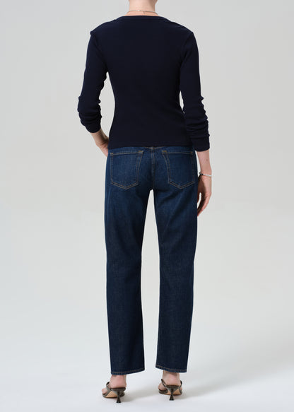 Person wearing a navy cardigan and dark blue jeans on a grey background