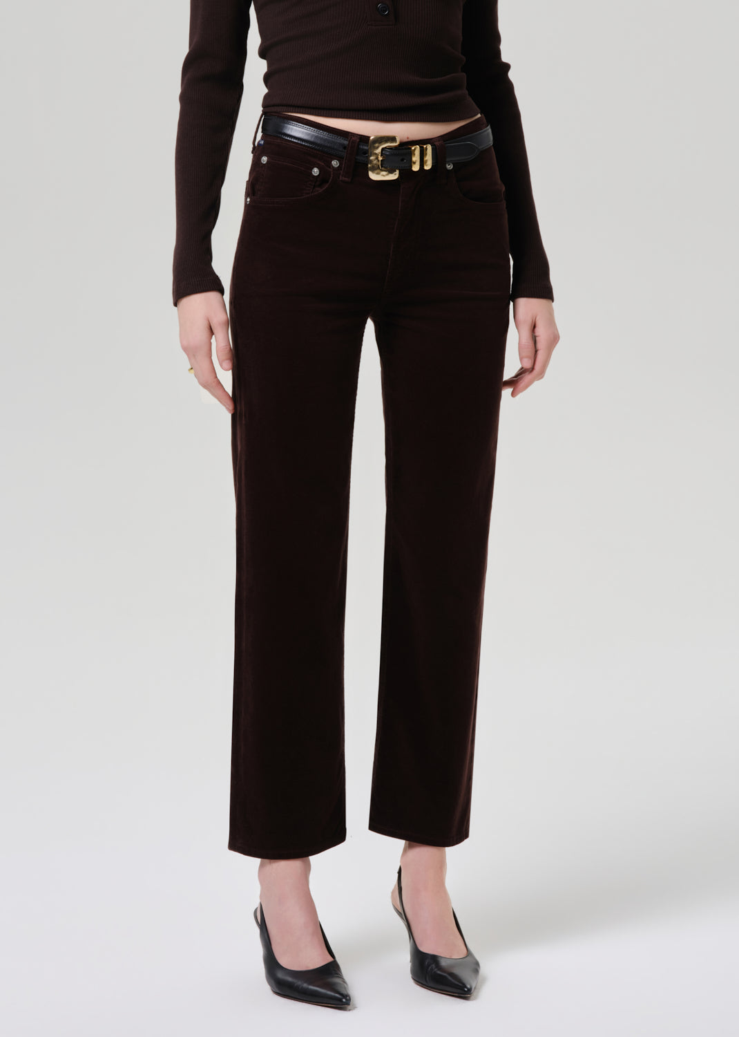 Person wearing black pants with a belt on a grey background