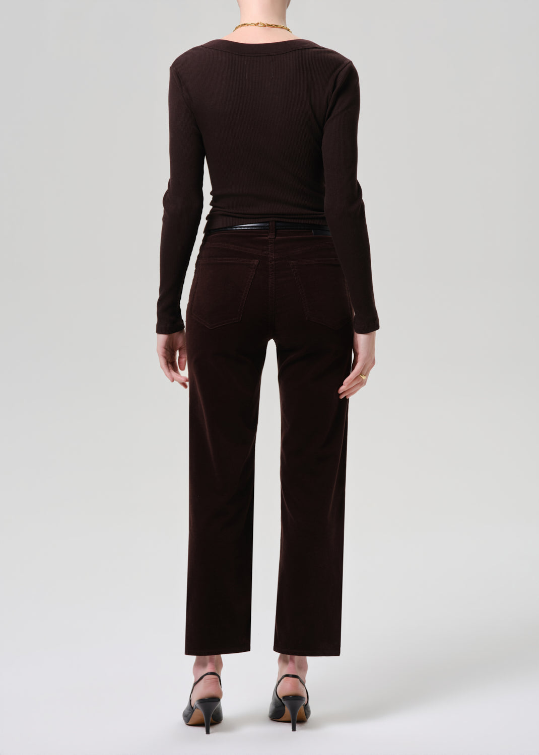 Person wearing a brown long-sleeve top and matching pants on a grey background