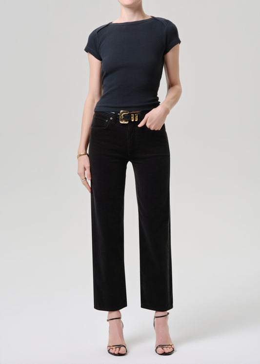 Person wearing a black t-shirt and black pants with a gold belt on a grey background