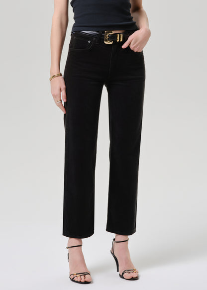 Person wearing black pants with a gold belt on a grey background