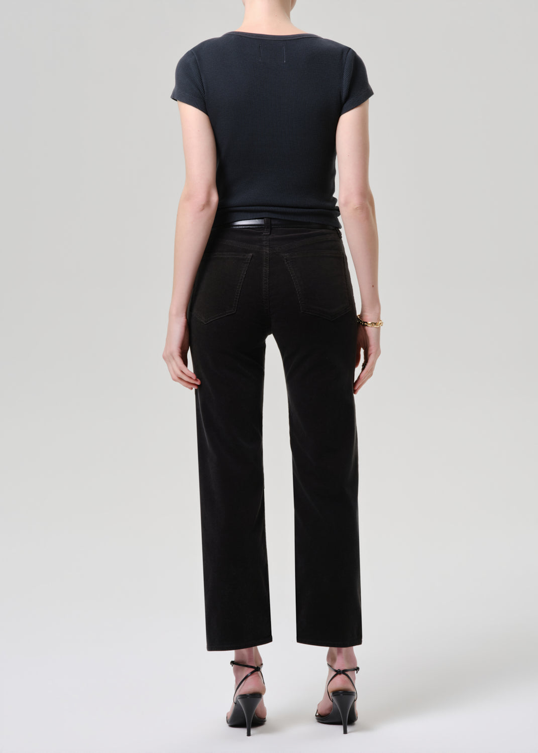 Person wearing a black t-shirt and black pants on a grey background