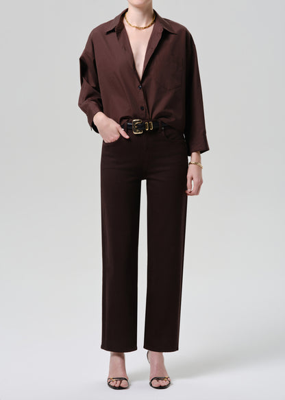 Person wearing a brown outfit with a belt on a grey background