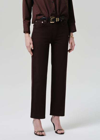 Person wearing a brown outfit with a belt on a grey background