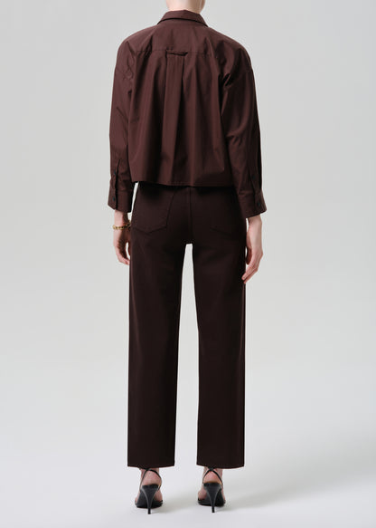Person wearing a brown shirt and pants on a grey background