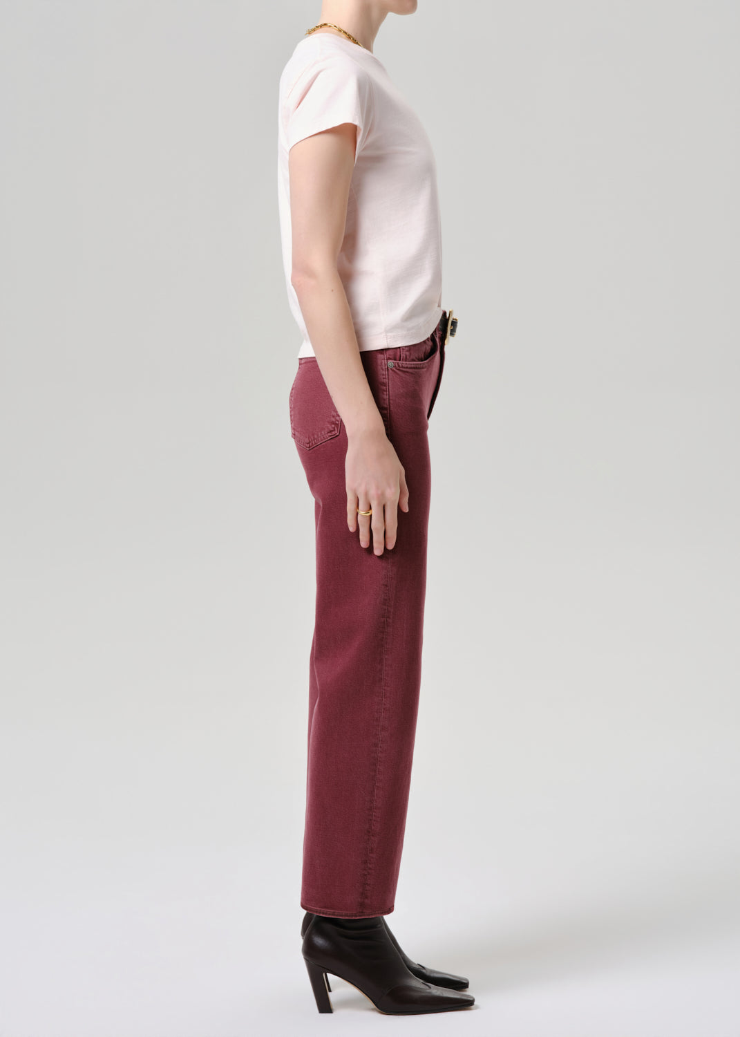 Person wearing a white top and maroon pants on a grey background