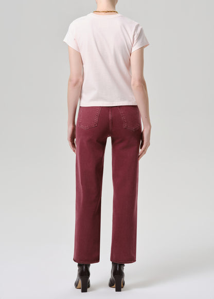 Person wearing a light pink t-shirt and burgundy pants on a grey background