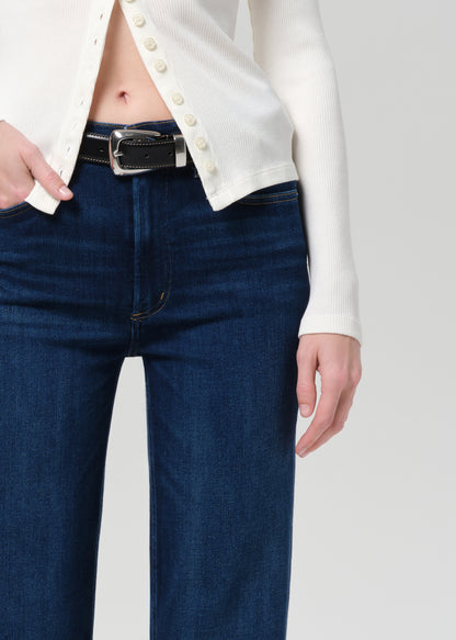 Person wearing blue jeans and a white button-up shirt on a plain background
