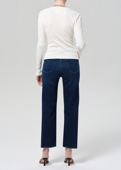 Person wearing a white long-sleeve shirt and dark blue jeans on a light gray background