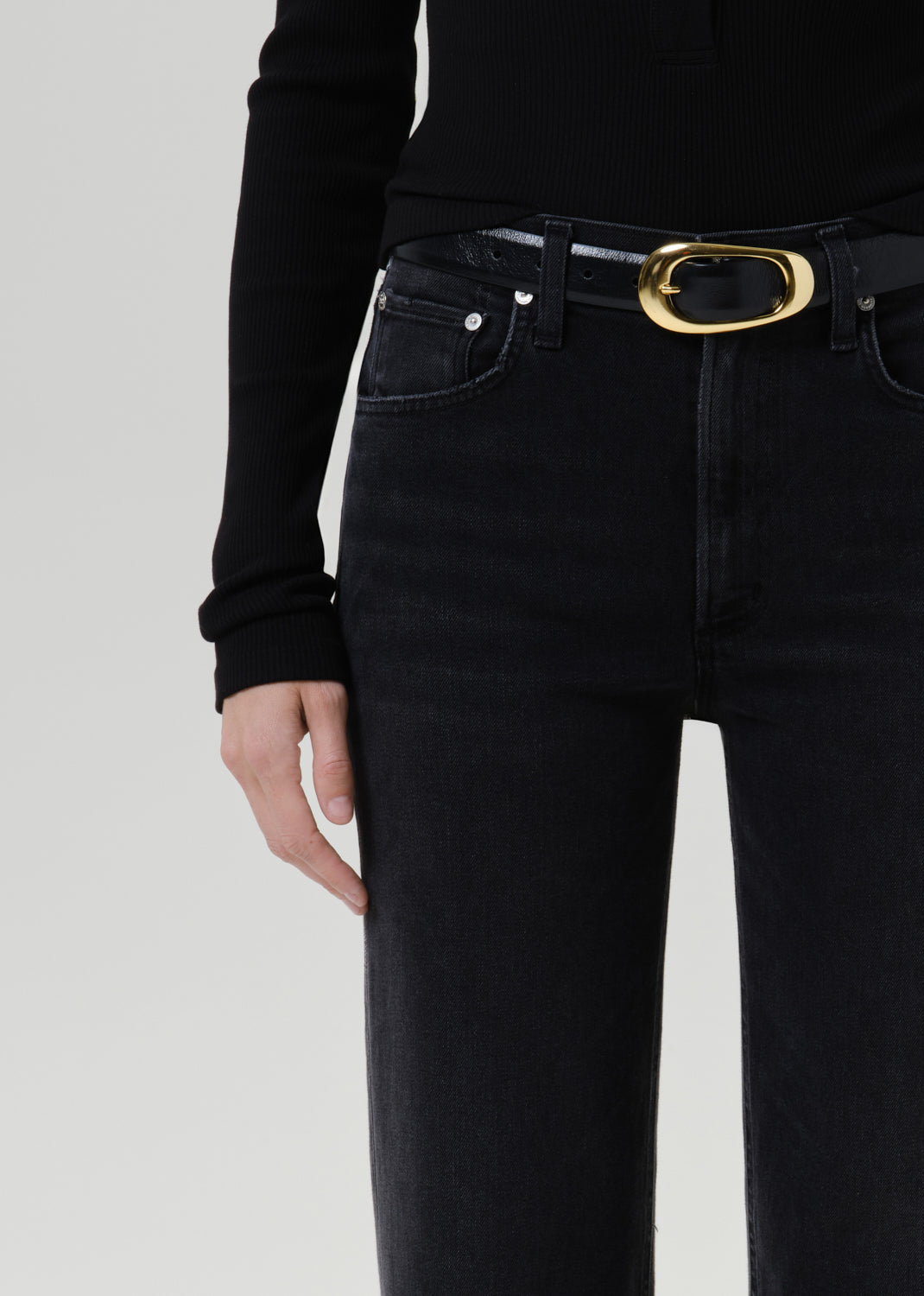 Close-up of black straight leg jeans with a black long sleeve henley top on a grey background
