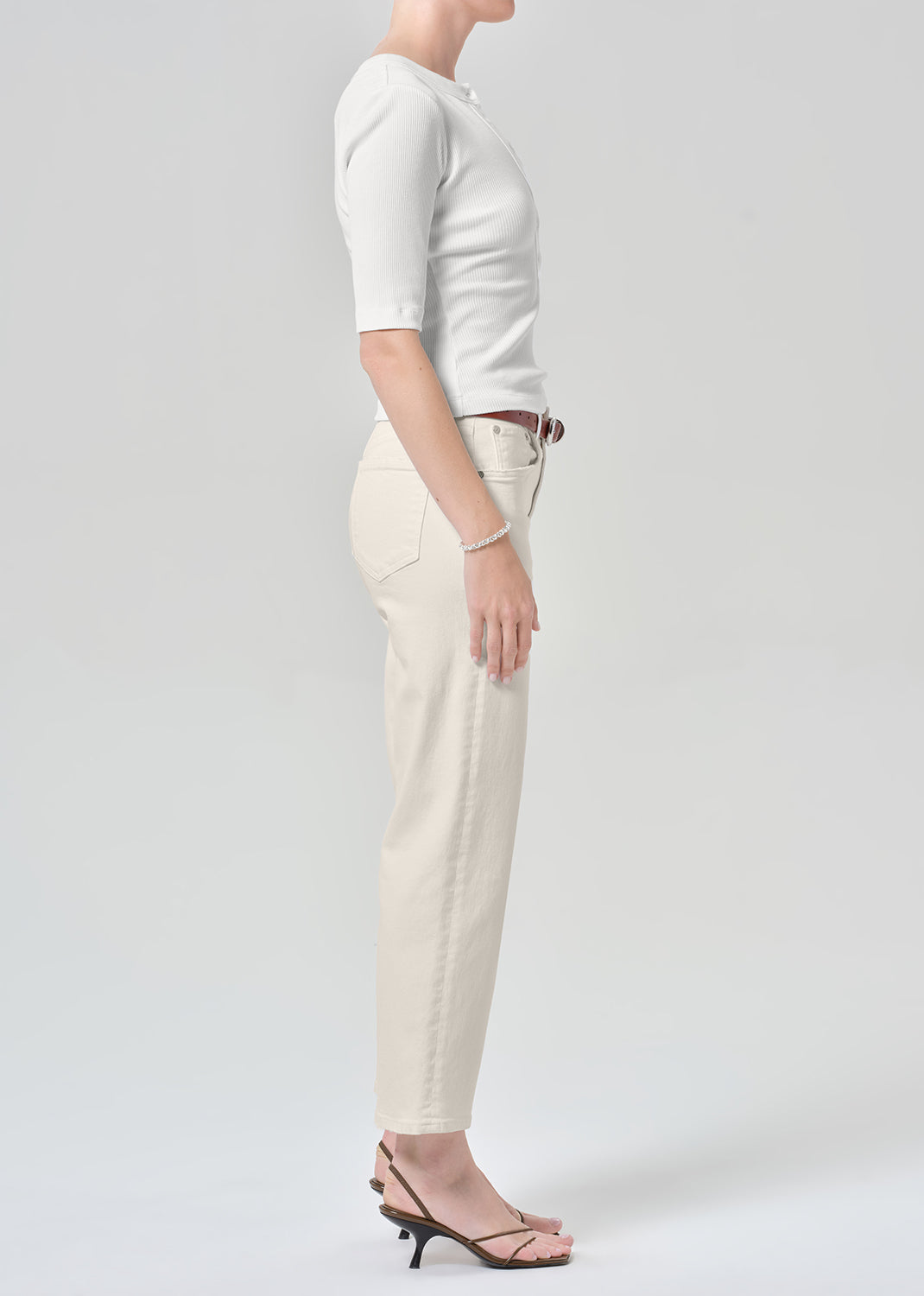 Persson wearing a white top with almond colored ankle jeans