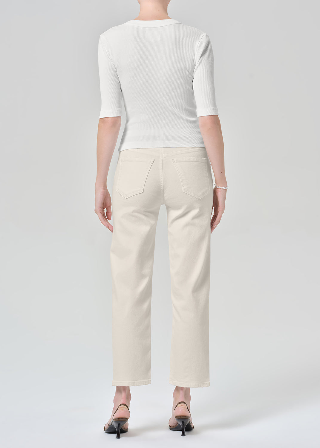 Persson wearing a white top with almond colored ankle jeans