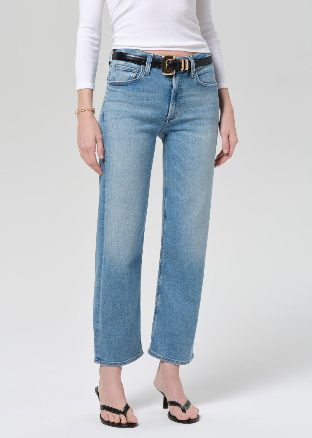 Person wearing light blue jeans with a white shirt on a plain background