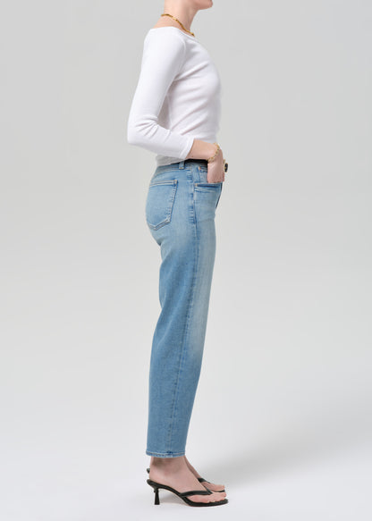 Person wearing light blue jeans and a white long-sleeve shirt on a plain background