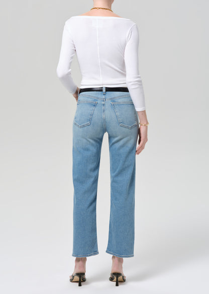 Person wearing light blue jeans and a white top on a plain background