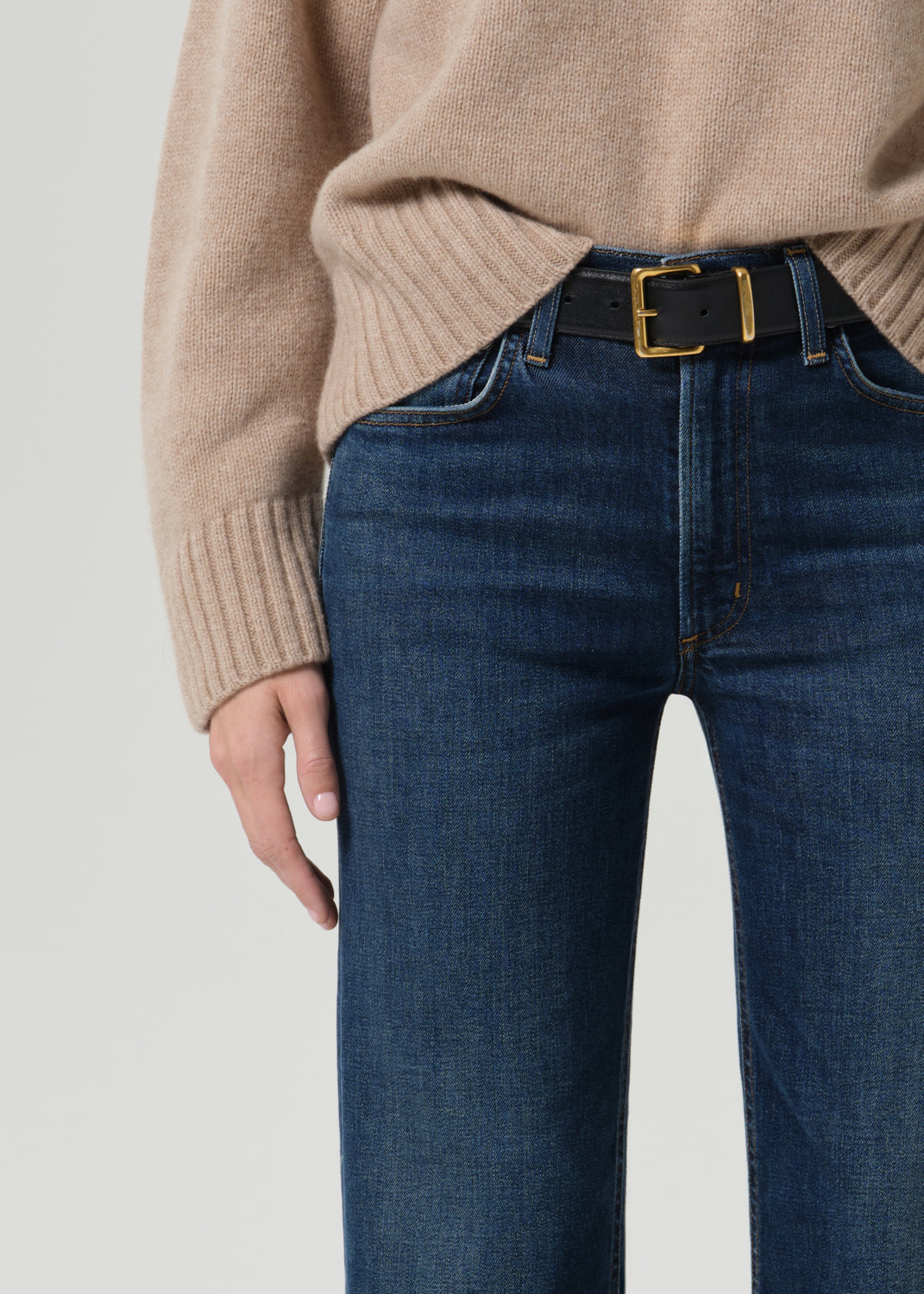 Close up of dark blue pants and black belt on a grey background