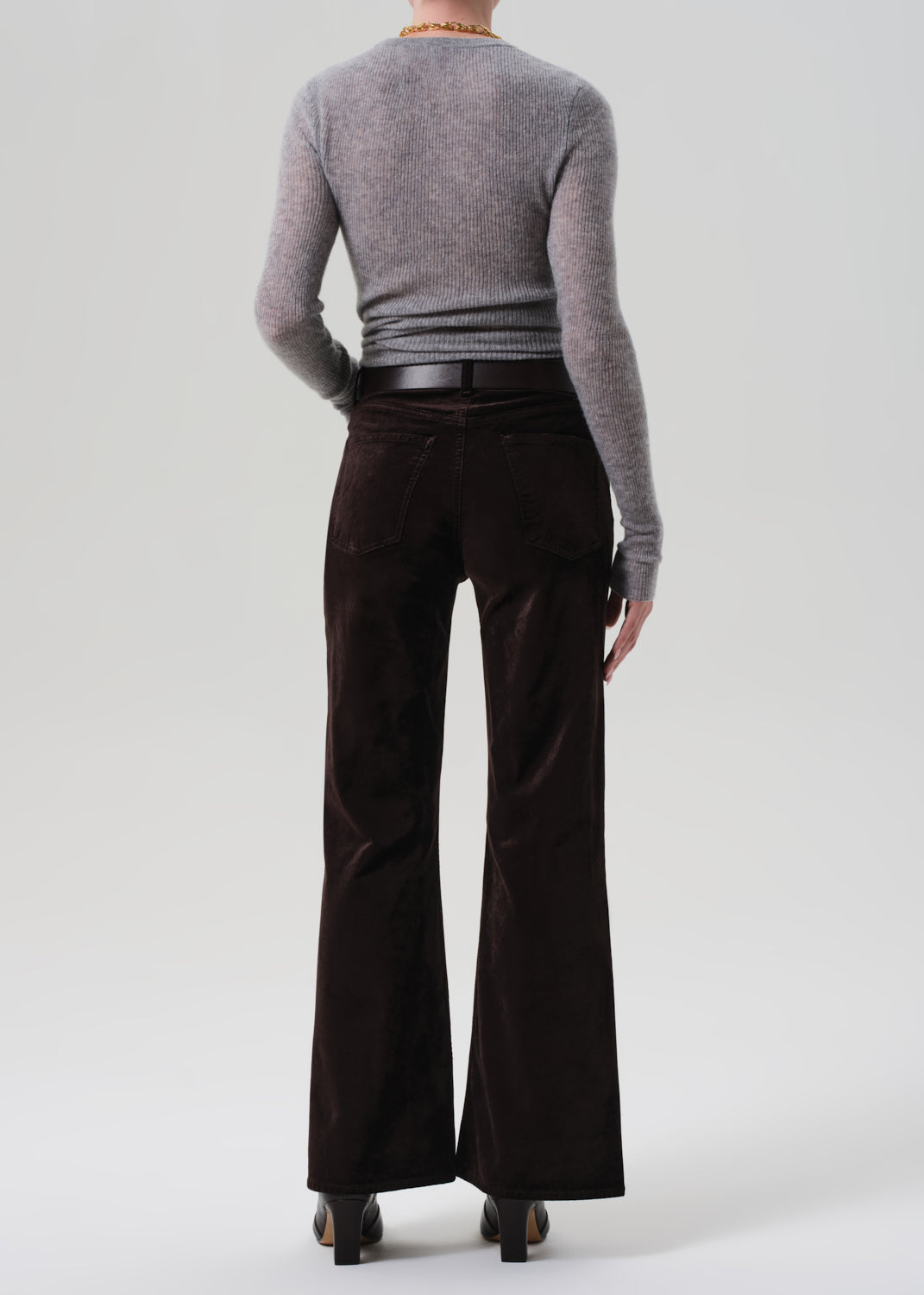 Person wearing a gray sweater and dark brown wide-leg pants on a white background