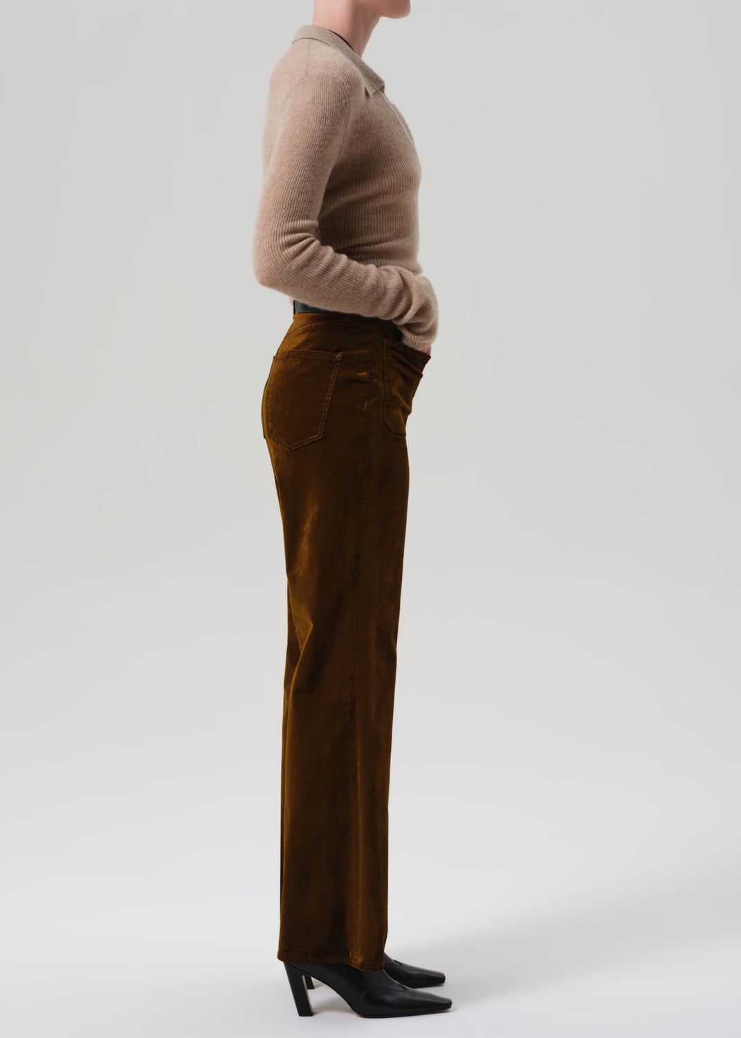 Person wearing a beige sweater and brown velvet flare-leg pants on a grey background
