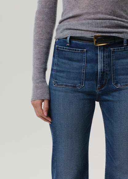 Person wearing blue jeans and a gray sweater on a plain background