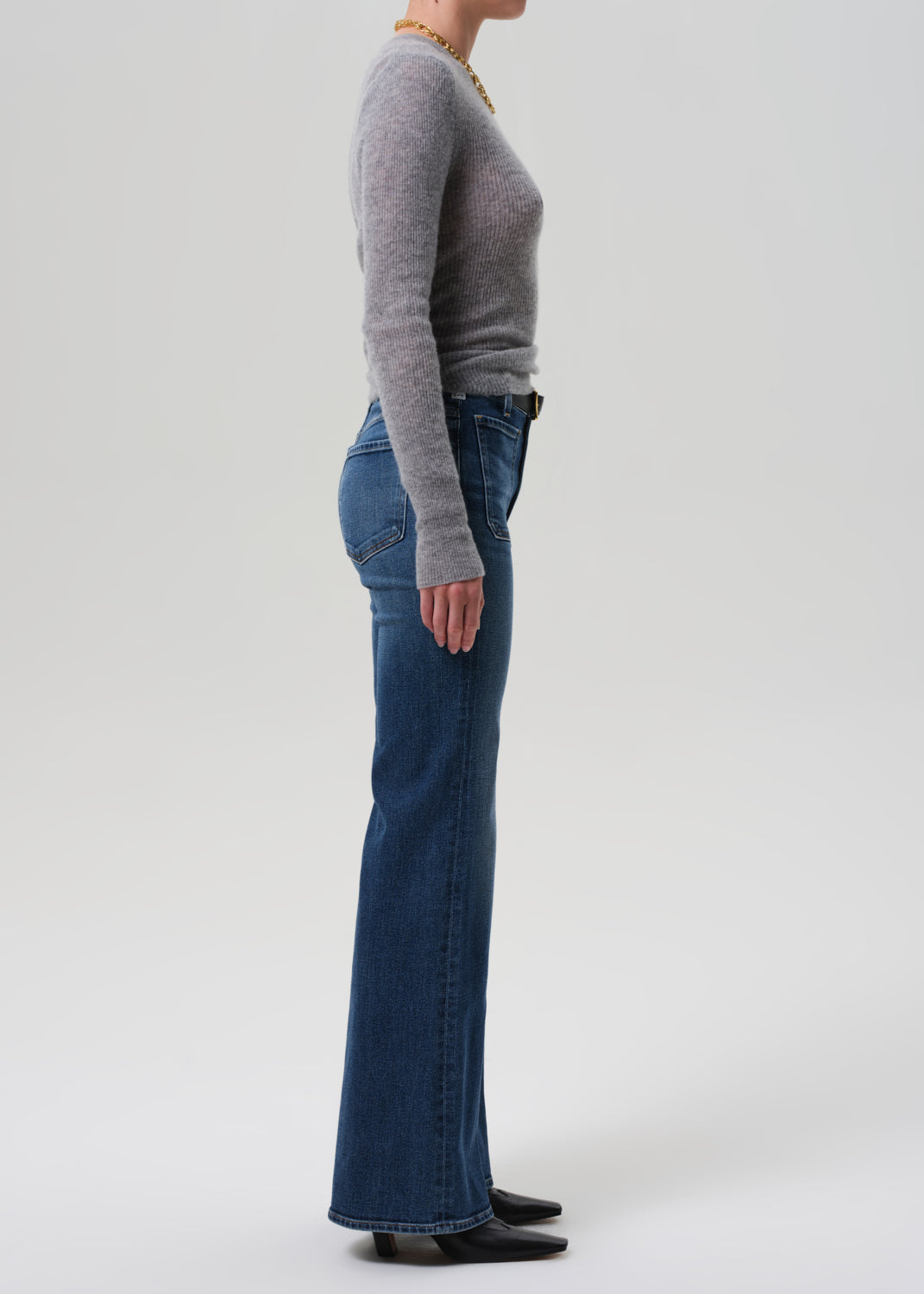 Person wearing a gray sweater and blue jeans on a white background