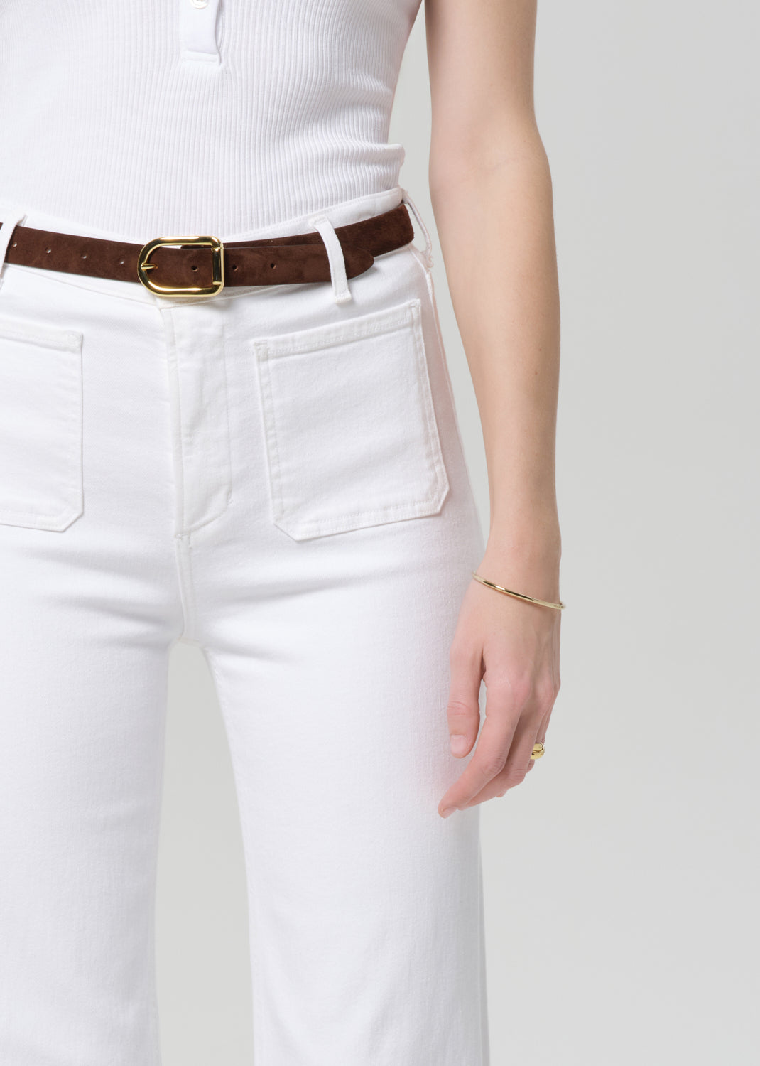 White pants with a brown belt on a plain background