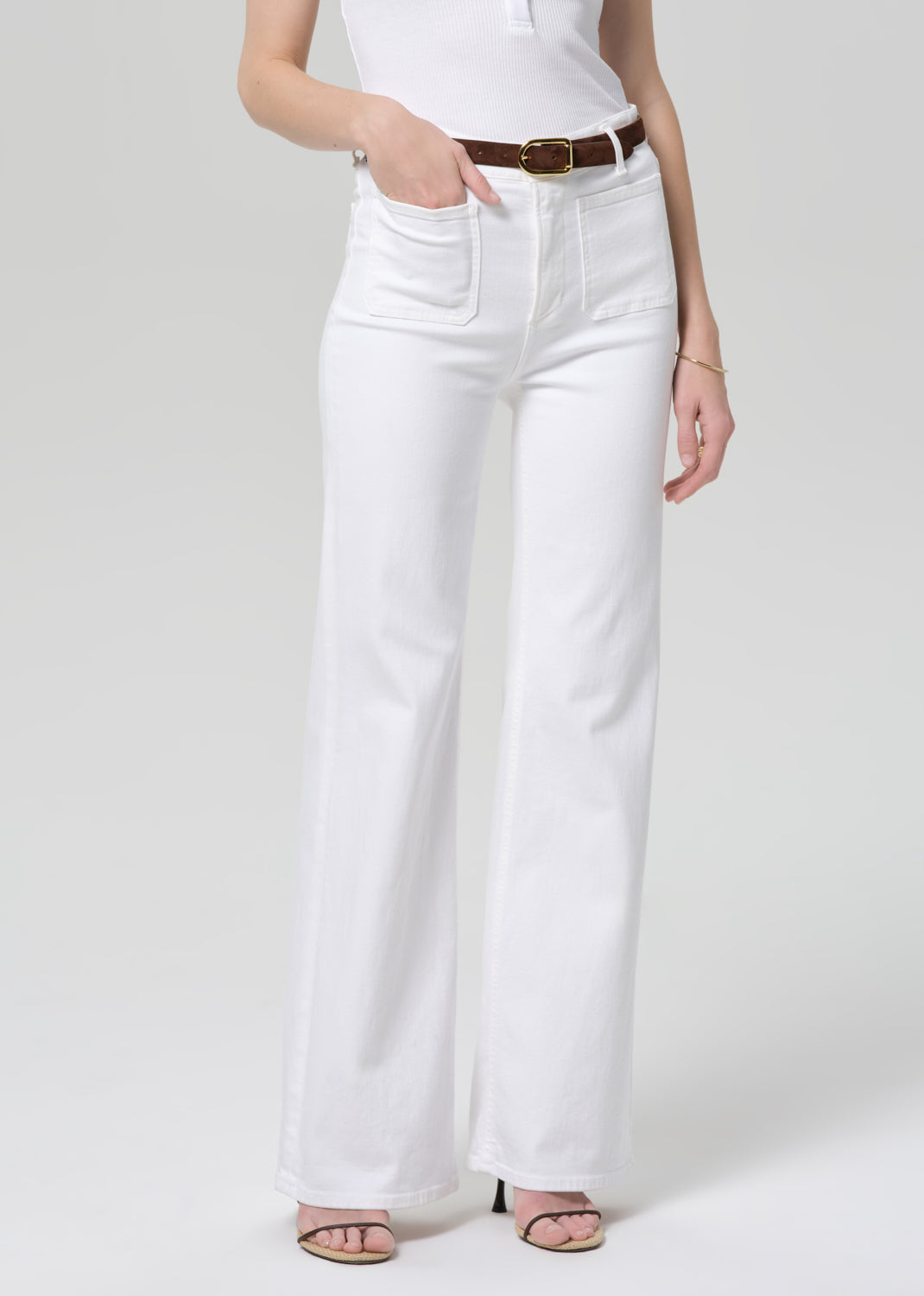 Person wearing white jeans and a white top on a plain background