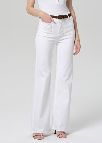 Person wearing white jeans and a white top on a plain background