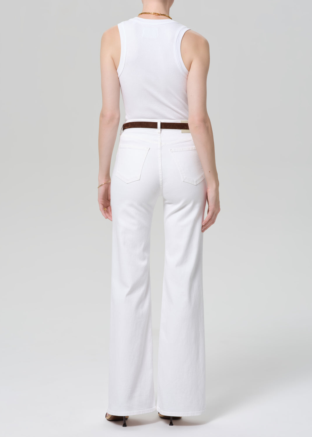 Person wearing a white sleeveless top and white wide-leg pants on a plain background