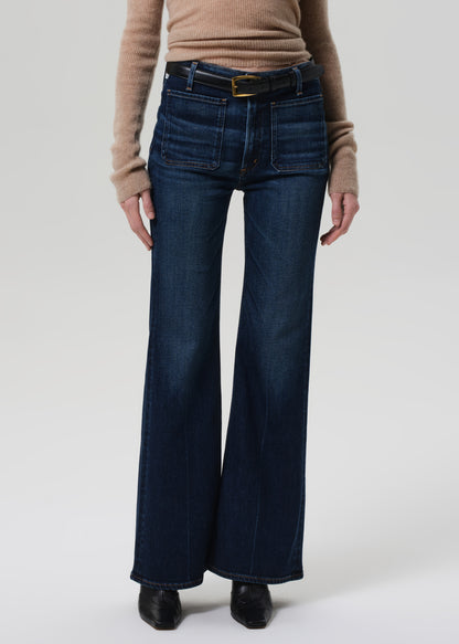 Person wearing blue flared jeans and a brown sweater on a white background