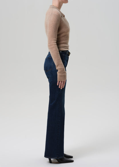 Person wearing a beige sweater and dark blue jeans on a white background