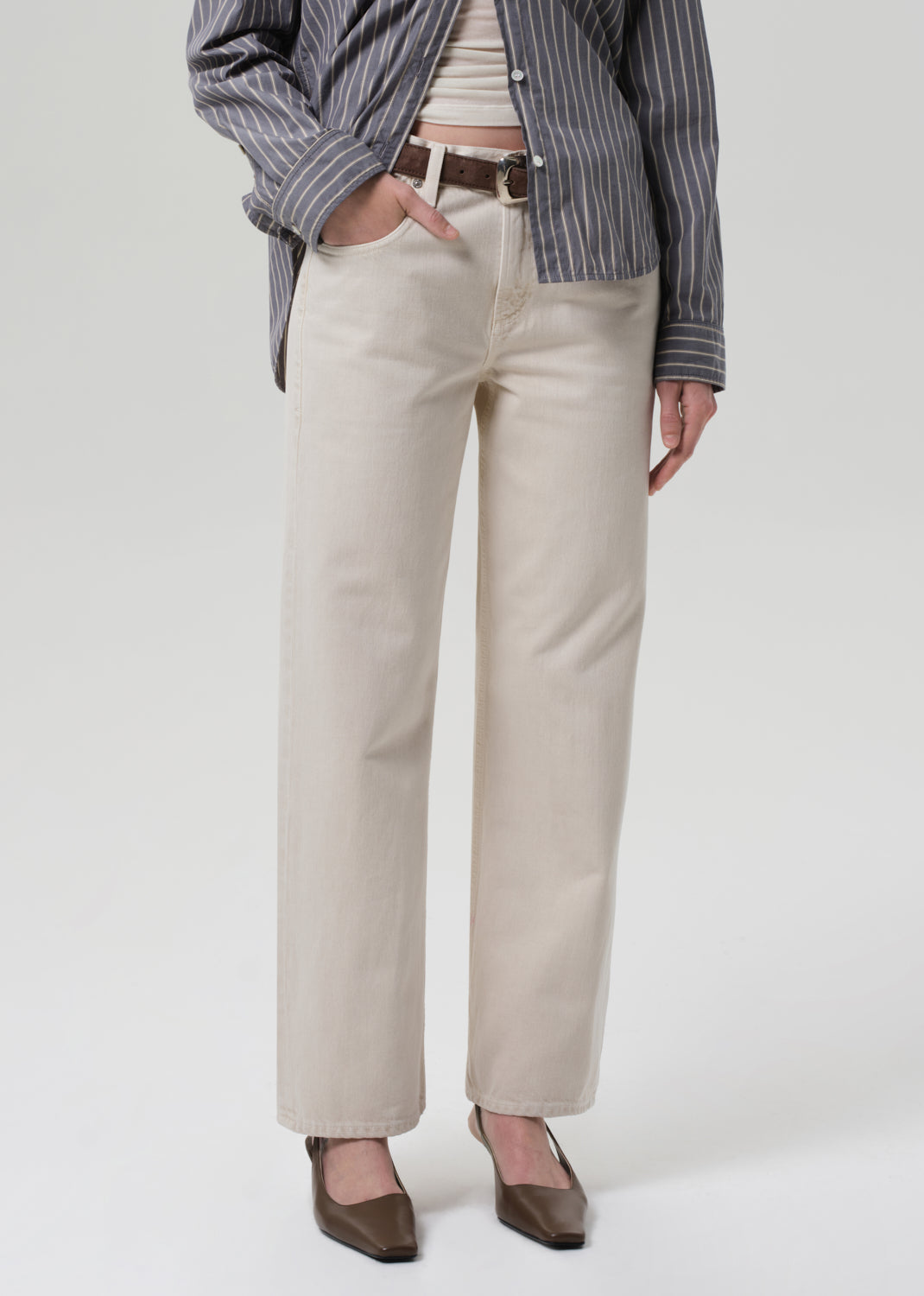 Person wearing beige pants with a striped shirt on a white background