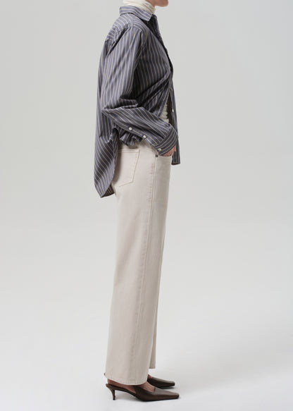 Person wearing a striped shirt and beige pants on a white background