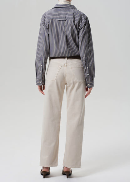 Person wearing a striped shirt and beige pants on a white background