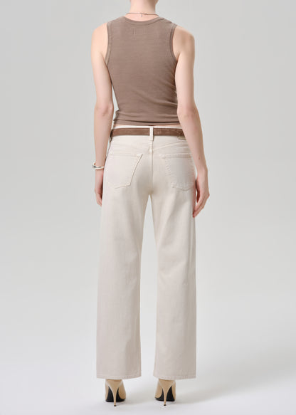 A model shown from the back wearing a sleeveless taupe-brown top, off-white wide-leg jeans, a brown belt, and beige heels against a grey background.