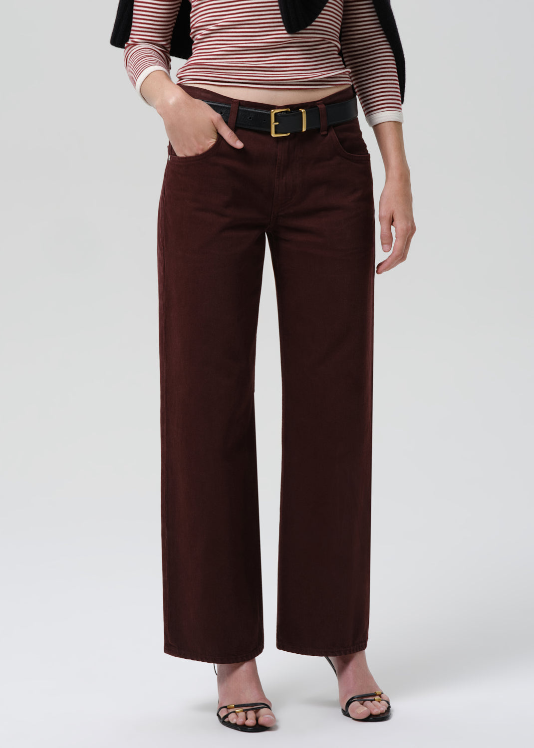 Person wearing a striped shirt and brown wide-leg pants on a grey background