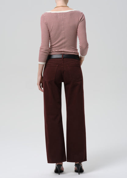 Person wearing a striped shirt and brown pants on a grey background