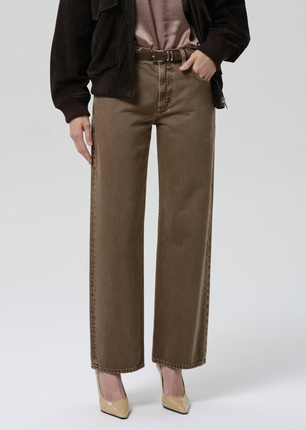 Person wearing brown wide-leg jeans on a grey background