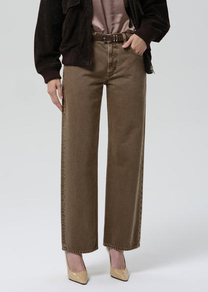 Person wearing brown wide-leg jeans on a grey background