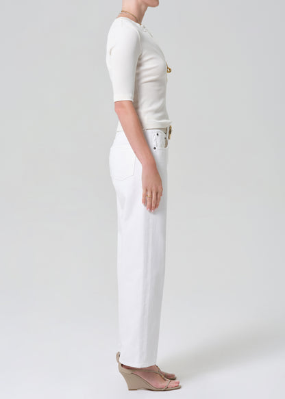 Person wearing a white shirt and white jeans with a belt on a plain background