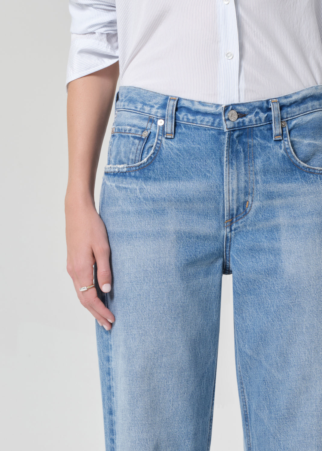 Person wearing a light blue shirt and jeans on a grey background