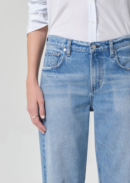 Person wearing a light blue shirt and jeans on a grey background
